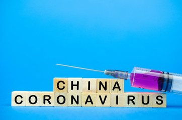 The inscription China Coronavirus and syringe on wooden cubes, blue background. Health concept, Chinese coronavirus