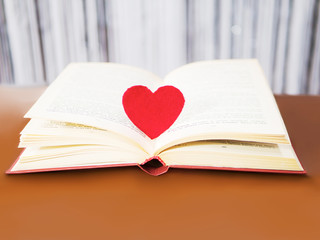 Red heart with old book concept. Greeting card for Valentine's day. Textile red heart for Valentines holiday. Romantic background and wallpaper