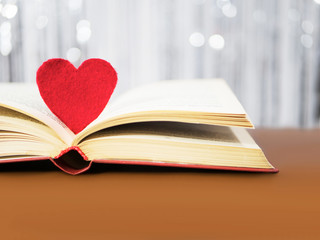 Red heart with old book concept. Greeting card for Valentine's day. Textile red heart for Valentines holiday. Romantic background and wallpaper