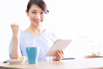 部屋でタブレットコンピューターを見る女性