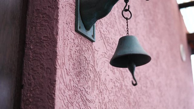 Old Antique Doorbell hanging on the wall. Guy hitting bell in front of doors at daytime. Isolated closeup.
