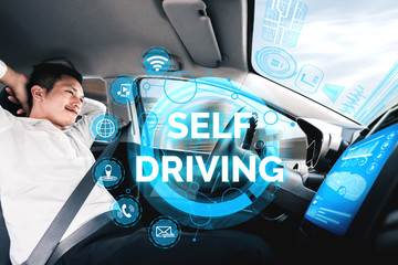 Self-driving autonomous car with relaxed young man sitting at driver seat is driving on busy highway road in the city. Concept of machine learning, artificial intelligence and augmented reality.
