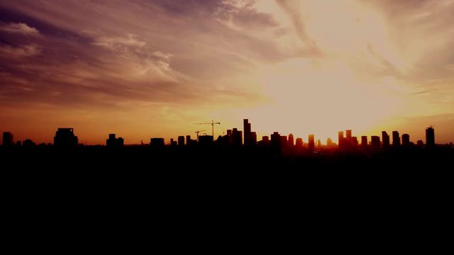 Aerial view over city skyline cityscape with high buildings in silhouette mood at sunset time