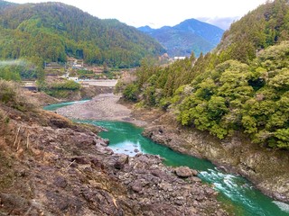 Japanese mountains and river on a cloudy day.
