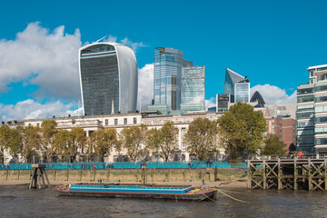 View of City of London District with Skyscrapers and a Boat in Thames River