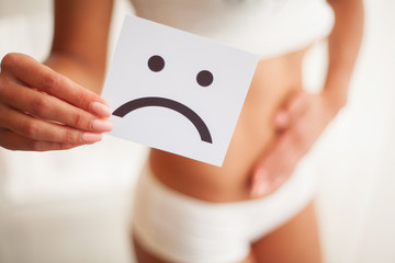 Woman Health. Female Body Holding Sad Smiley Card Near Stomach.