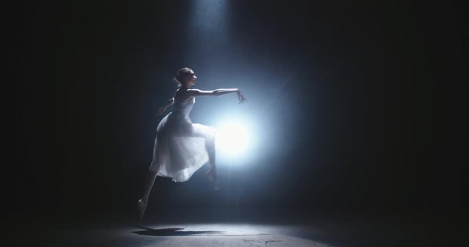 Female ballet dancer performing on spotted stage, douing various movements and pirouettes - arts, success concept 4k footage