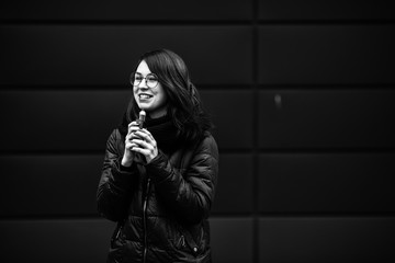Vape teenager. Young pretty white caucasian girl in a jacket and glasses smoking an electronic...
