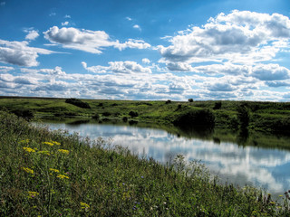 A river surrounded by hills, fields and forests in summer in Russia
