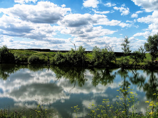 A lake surrounded by fields and forests in summer in Russia