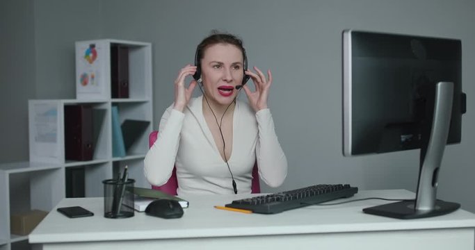 Call center operator is tired of talking to people asking stupid questions. Young customer service representative at work. Young female worker productively operating at call-centre.
