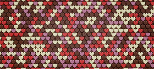Fototapeta premium 小さなハートの形のチョコレートが規則的に並んだ背景画像。