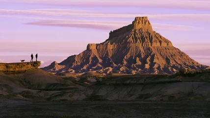 Fototapeten young women and dog overlooking view of bold desert landscape at sunrise sunset © jamesdcawley