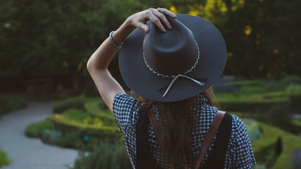 young woman wearing hat in garden at sunset
