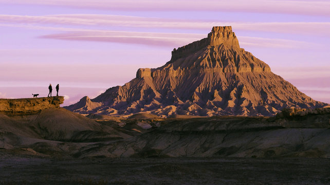 young women and dog overlooking view of bold desert landscape at sunrise sunset
