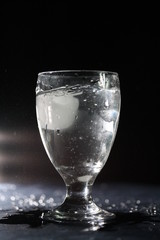 Glass of refreshing not carbonated water with ice in a glass, isolated on black