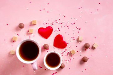 Love drinks. Coffee tea cups for two, sweets candy chocolate on pink hearts background. Valentines day 14 february minimal concept