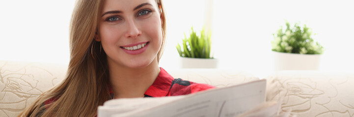 young blond pretty woman drinking coffe and reading in morning sit on sofa