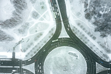 road roundabout covered with white fresh snow. aerial top view of city suburb area