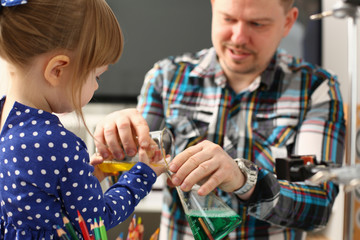Man and little girl play with colourful liquids portrait. Young team clean research equipment...