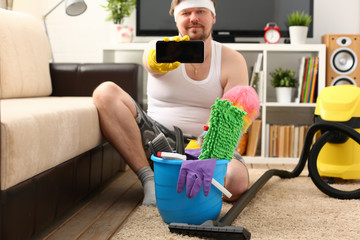 A young smiling man holds a smartphone in his hand demonstrating it to the camera advertising a...