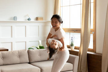 Overjoyed Vietnamese mom and small daughter have fun at home