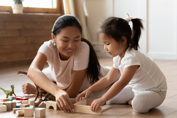 Asian young mom and little daughter play building bricks