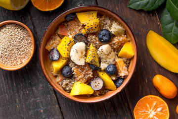Fresh quinoa organic fruit salad in bowl on wooden  background. Helthy superfood detox concept.  Vegan/vegetarian food. Space for text. Top view