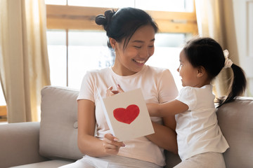 Little Asian girl greeting mom presenting postcard