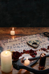 Mystic ritual with Ouija and candles. Devil's board concept, black magic or fortune telling rite...