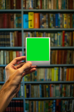 Holding Polaroid In Front Of Bookshelf (portrait)