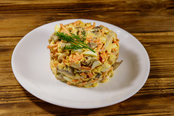 Tasty salad with chicken breast, roasted mushrooms, carrots, grated cheese, eggs and mayonnaise on wooden table