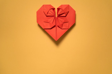 red origami paper heart on yellow background, valentines day greeting card