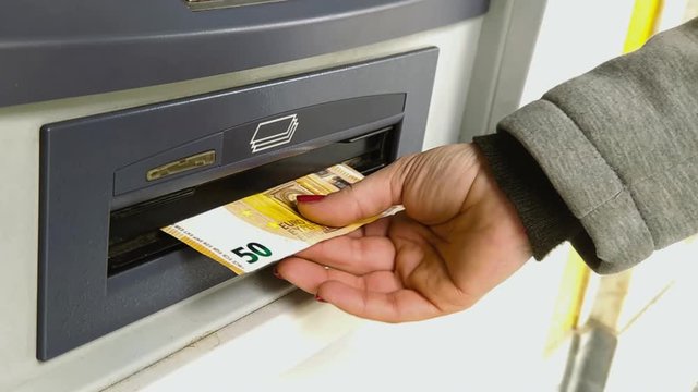 Woman withdraws 50 euro banknotes from an ATM