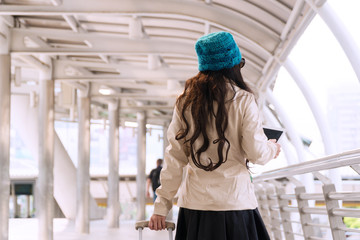 Back of traveler young woman wearing green hat holding tablet in her hands guide directions searching to some way while alone walking in the city. Travel tourism, technology concept.