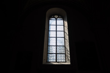 Fototapeta na wymiar Front view of light through a Gothic stone church window among the dark background , copy space , wallpaper