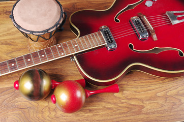 Fototapeta na wymiar Jazz electric guitar, maracas and djembe on a wooden texture.