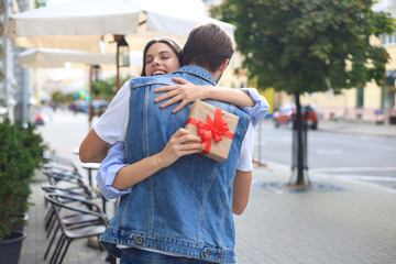 Fototapeta premium Image of attractive woman with present box giving hug to her man.