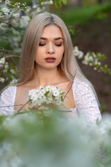 beautiful blonde girl in spring cherry garden