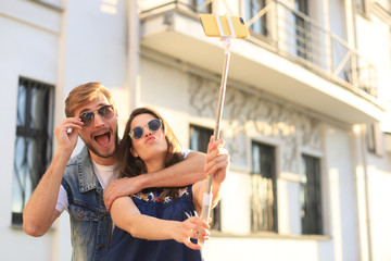 Beautiful lovely young couple walking at the city streets, hugging while taking a selfie.