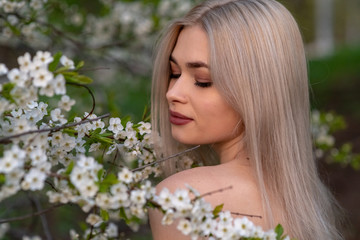 Naklejka premium beautiful blonde girl in spring cherry garden