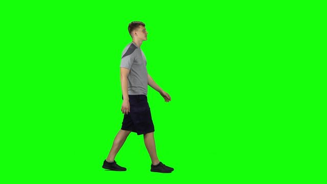 Young man walking on a Green Screen. Profile side view