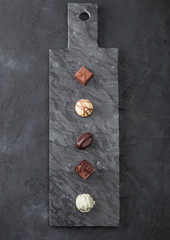 Luxury Chocolate candies selection on black marbel board. White, dark and milk chocolate assortment.