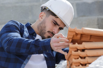 roofer collecting clay tile from stack - obrazy, fototapety, plakaty