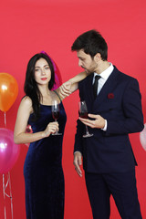 Sweet couple Love smile and spending Romantic with drinking wine in christmas time and celebrating new year eve, valentine day with colorful balloon on red background