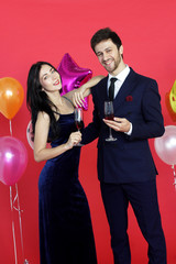 Sweet couple Love smile and spending Romantic with drinking wine in christmas time and celebrating new year eve, valentine day with colorful balloon on red background