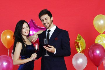 Sweet couple Love smile and spending Romantic with drinking wine in christmas time and celebrating new year eve, valentine day with colorful balloon on red background