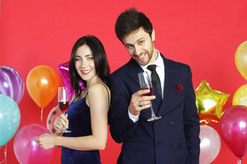 Sweet couple Love smile and spending Romantic with drinking wine in christmas time and celebrating new year eve, valentine day with colorful balloon on red background