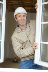 happy construction worker installing window in house