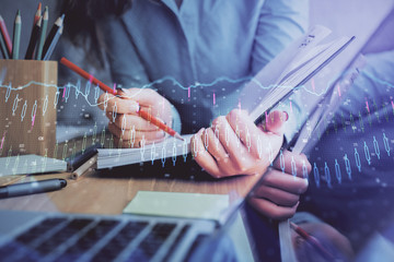 A woman hands writing information about stock market in notepad. Forex chart holograms in front. Concept of research. Multi exposure